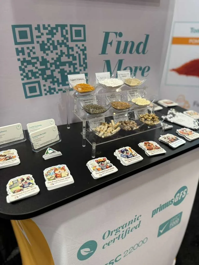 APS Phoenix Booth 1026 tabletop at Petfood Forum 2026 with ingredient samples, the Find More QR panel, and certifications strip.